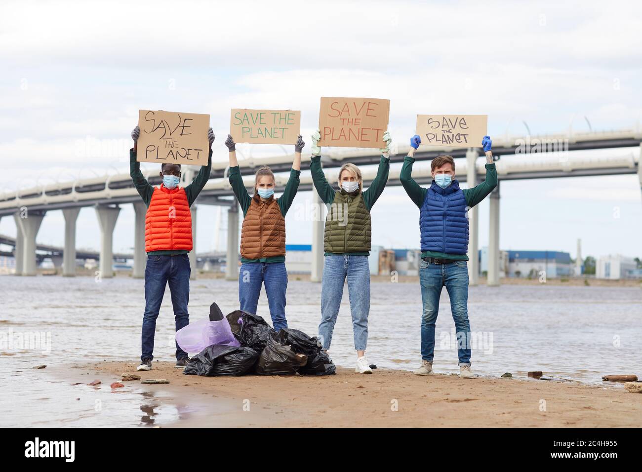 Groupe de bénévoles qui élèvent des plaques près des sacs de déchets près de la côte Banque D'Images