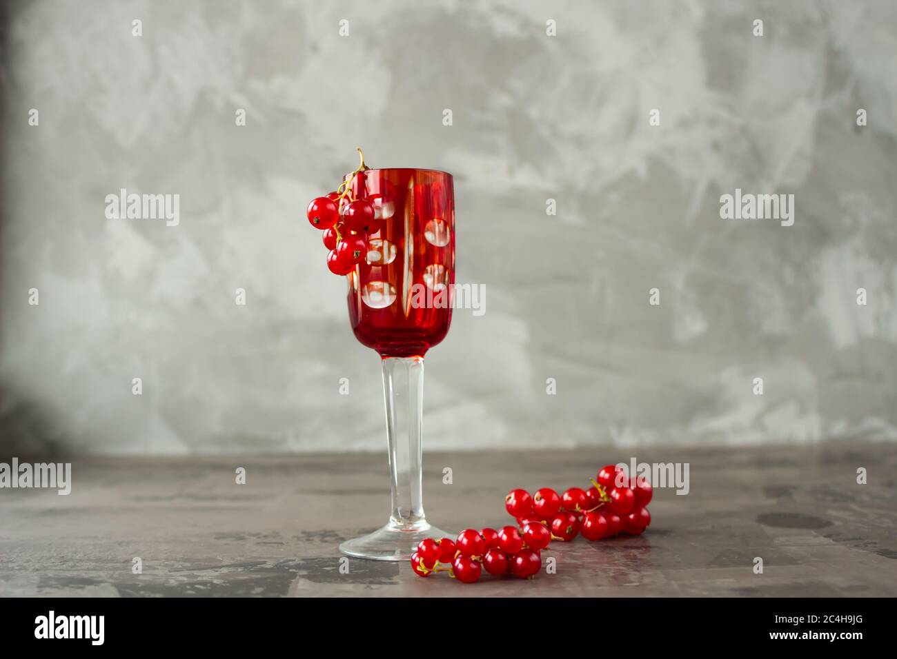 Cassis dans un verre à grenaille, le reste est dispersé autour d'elle sur un fond gris texturé. Photo de haute qualité Banque D'Images