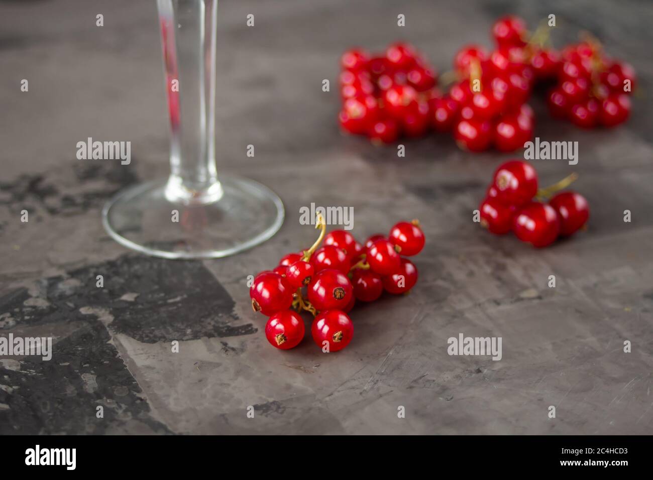 Cassis dans un verre à grenaille, le reste est dispersé autour d'elle sur un fond gris texturé. Photo de haute qualité Banque D'Images