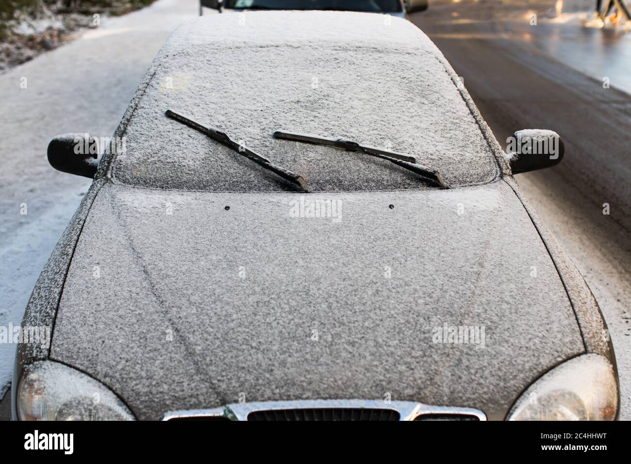 Vue avant des essuie-glaces et du pare-brise de voiture givré recouvert de glace et de neige. Banque D'Images
