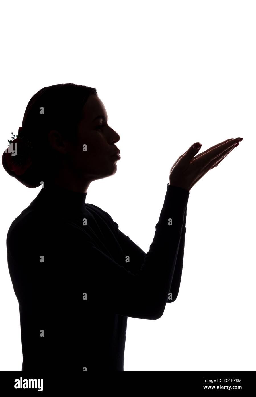Une jeune femme montre ses mains en avant, envoyant un baiser - silhouette Banque D'Images