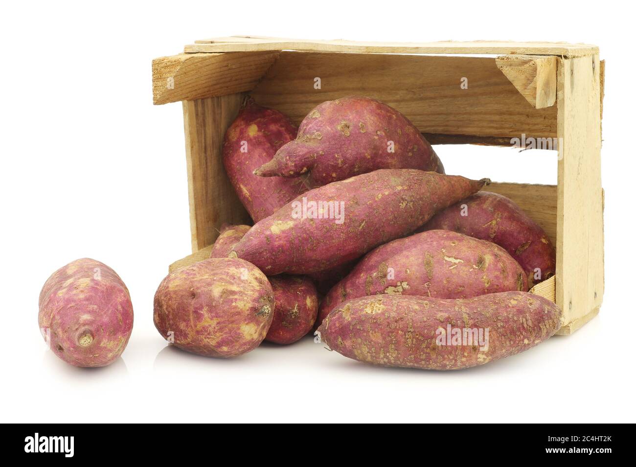 patates douces fraîchement récoltées dans une caisse en bois sur fond blanc Banque D'Images