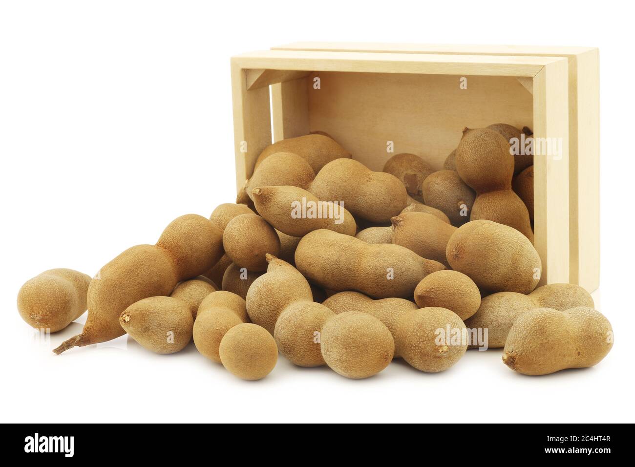 Haricots de Tamarind dans une boîte en bois sur fond blanc Banque D'Images