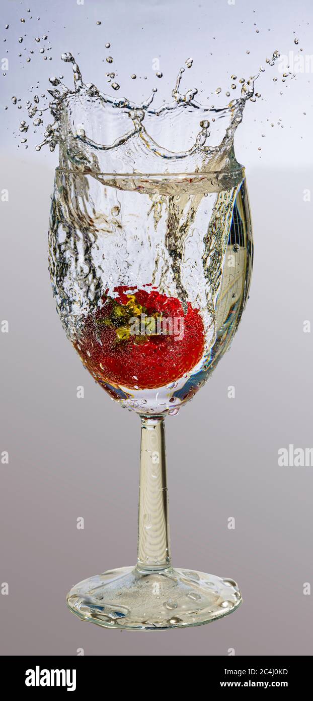 Photo macro rapide d'une fraise tombée dans un verre de vin Banque D'Images