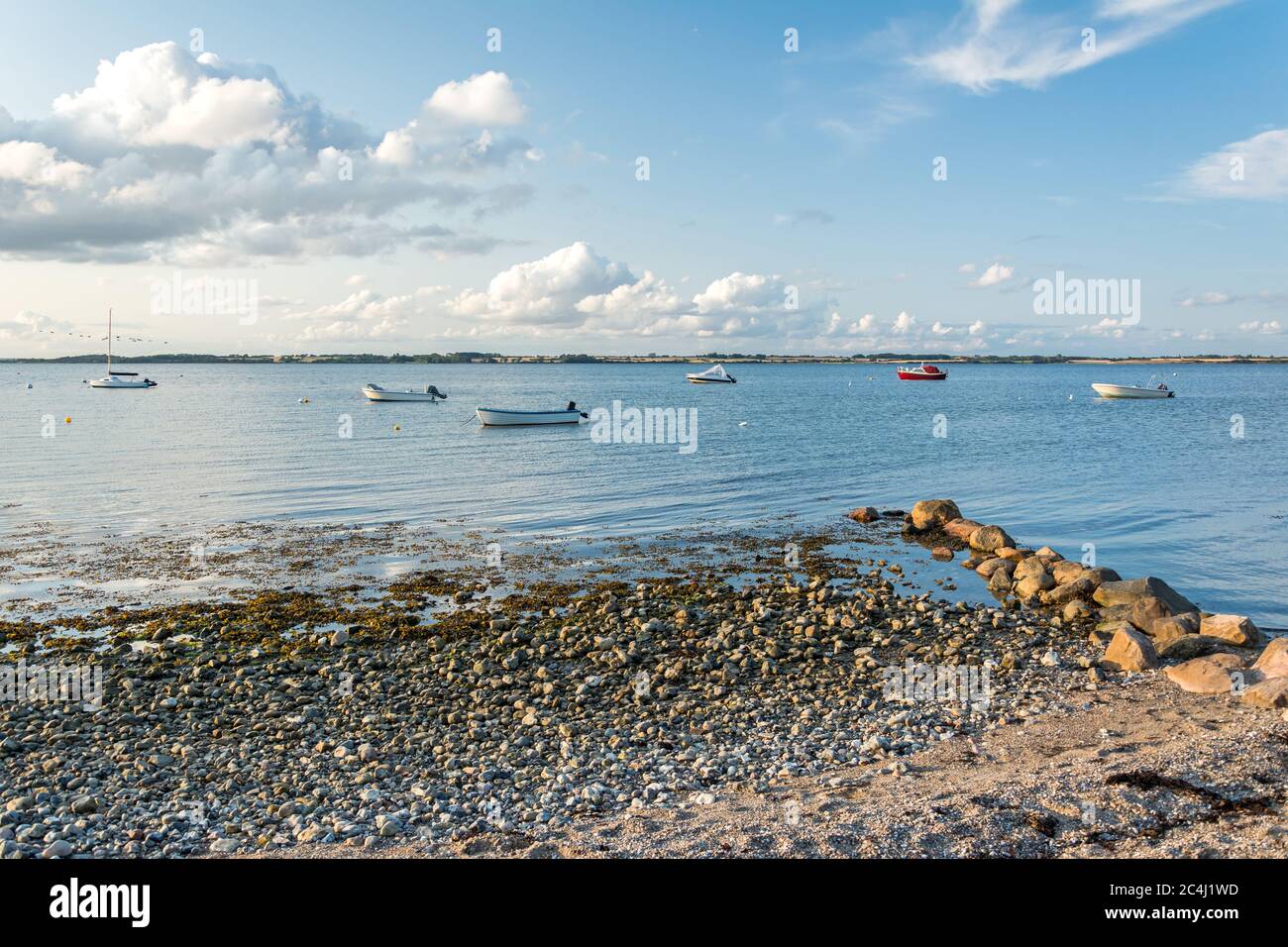 Plage de sable pittoresque et rochers avec des bateaux en arrière-plan à la mer Baltique dans le nord de l'Allemagne Banque D'Images