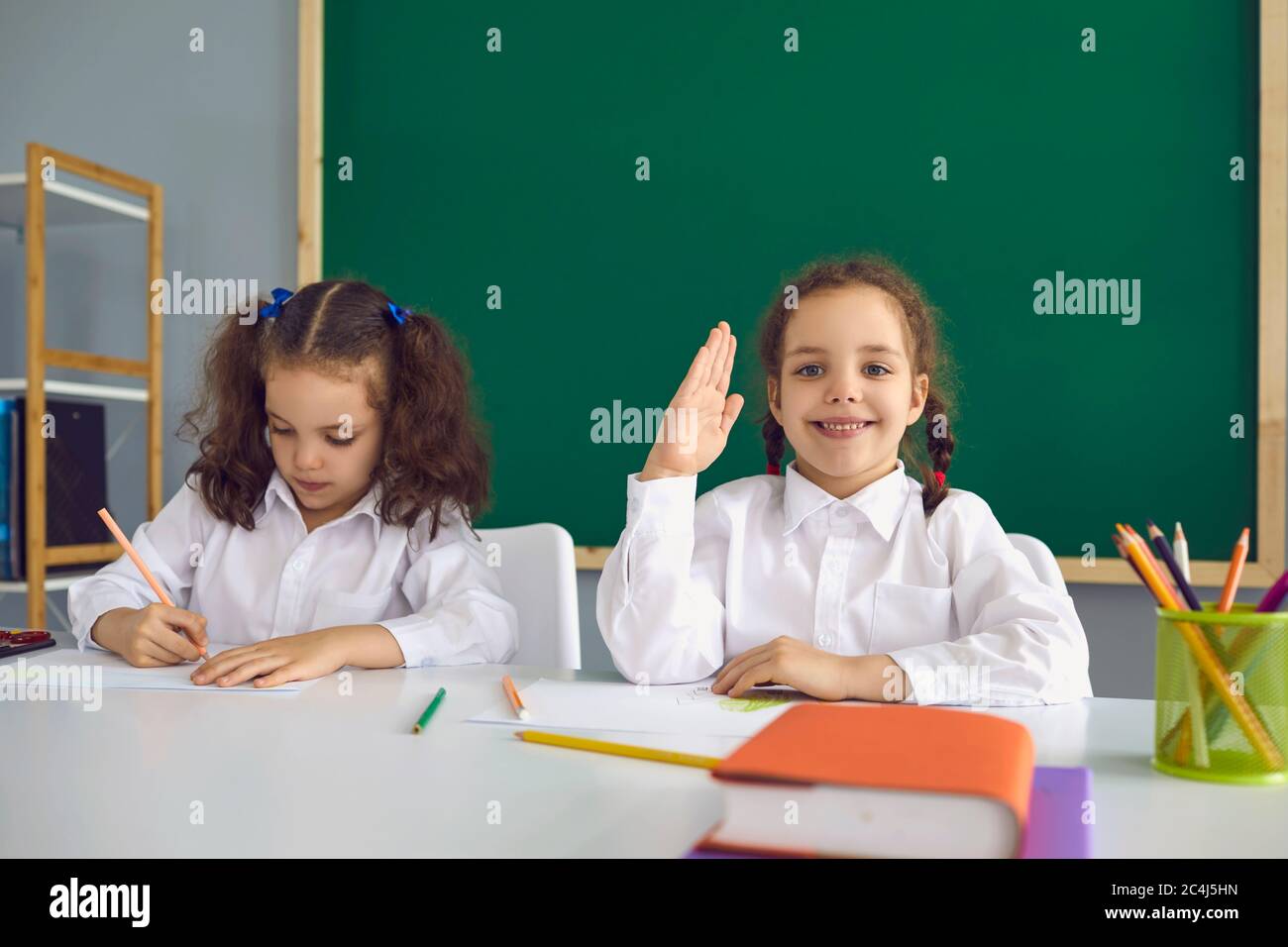 Retour à l'école. Les écolières à une conférence assise à la table dans la salle de classe. Banque D'Images