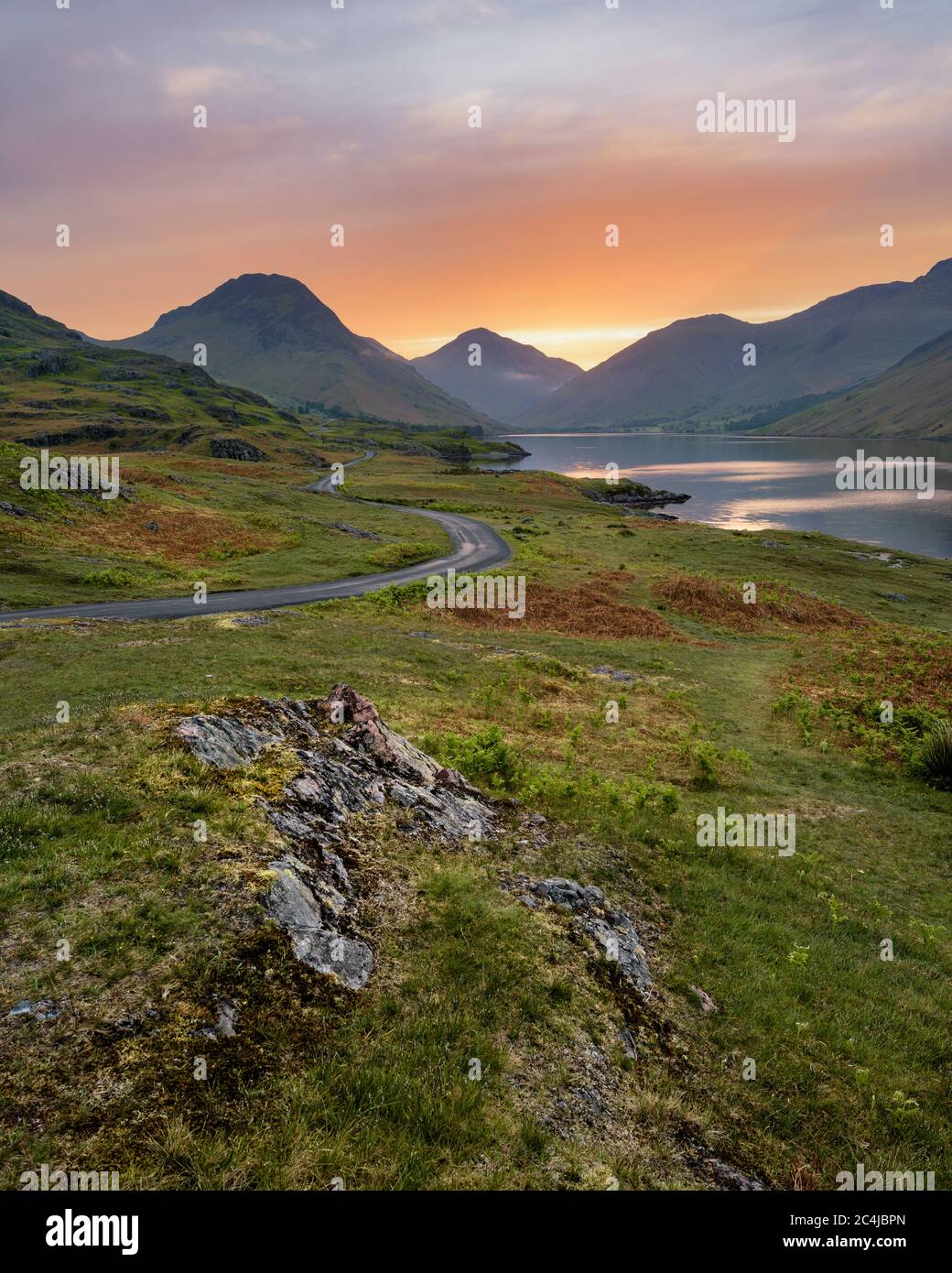 Sinueuse route à voie unique menant à travers la campagne verte isolée avec belle Sunrise. Wastwater, Lake District, Royaume-Uni. Banque D'Images