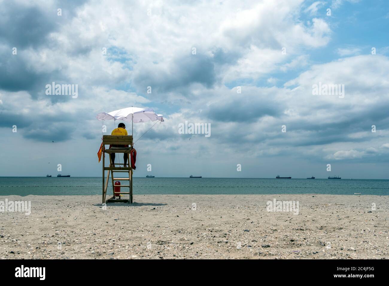 Un maître de sauvetage assis sur la tour de surveillance, en face de la  mer. Chaise de plage de maître-nageur. Maître nageur de plage. Ciel nuageux  Photo Stock - Alamy