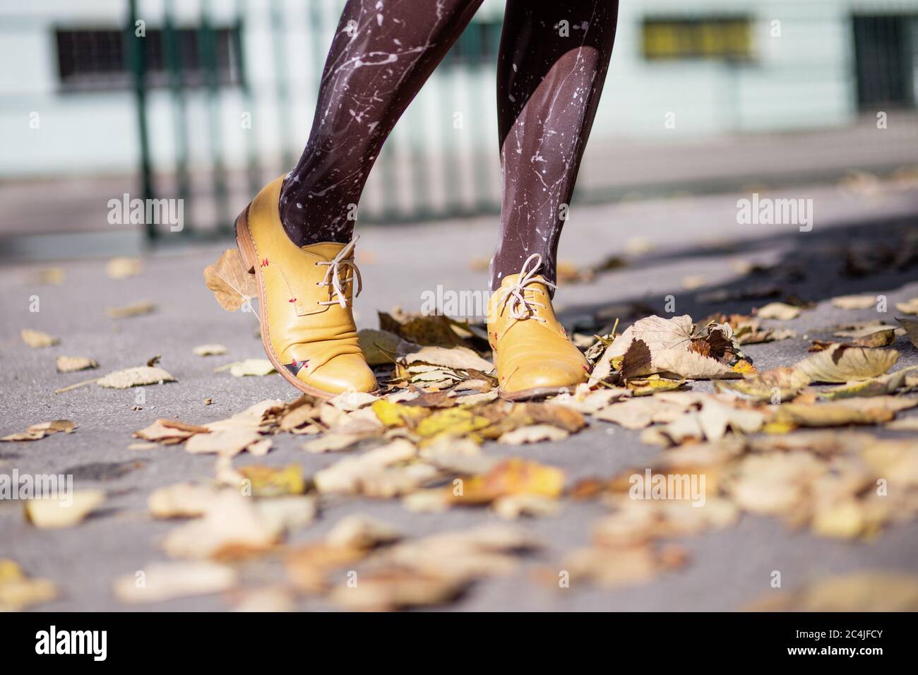 Jambes de femme en chaussures jaunes sur les feuilles d'automne Banque D'Images