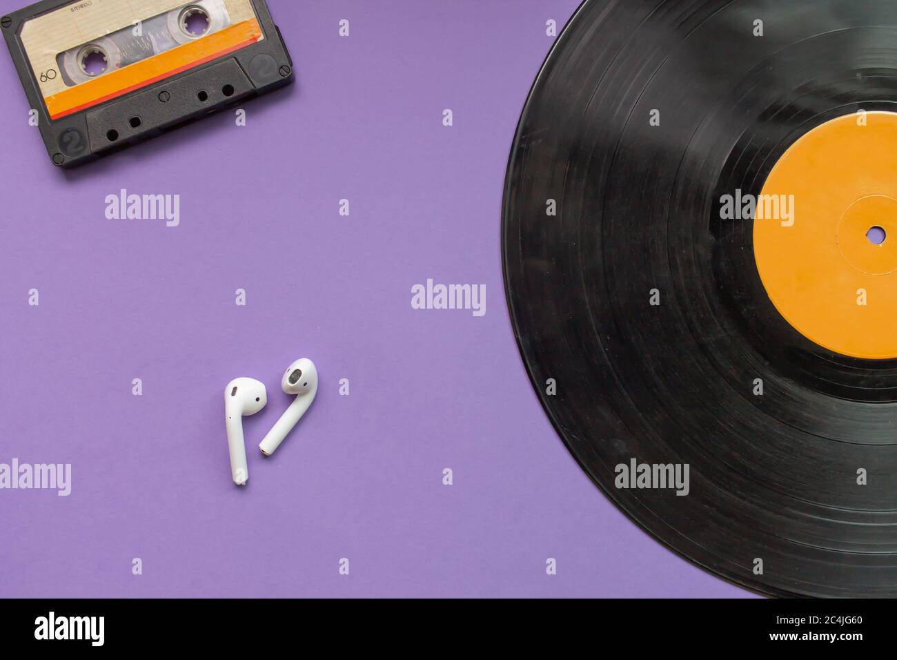 vue de dessus d'un disque en vinyle longue durée, d'un casque noir et d'une cassette audio sur fond violet. Concept de l'évolution de la musique. Banque D'Images