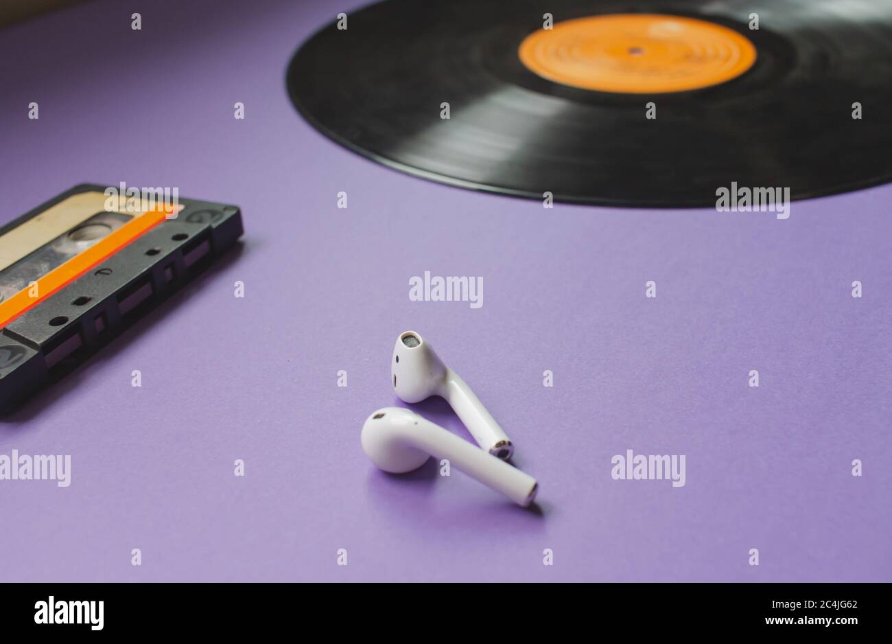 vue de dessus d'un disque en vinyle longue durée, d'un casque noir et d'une cassette audio sur fond violet. Concept de l'évolution de la musique. Banque D'Images
