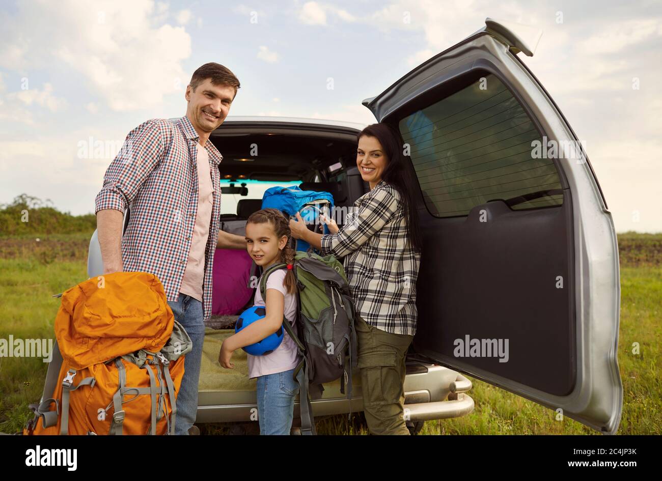 Famille souriante de voyageurs en voiture debout dans la nature en été. Banque D'Images