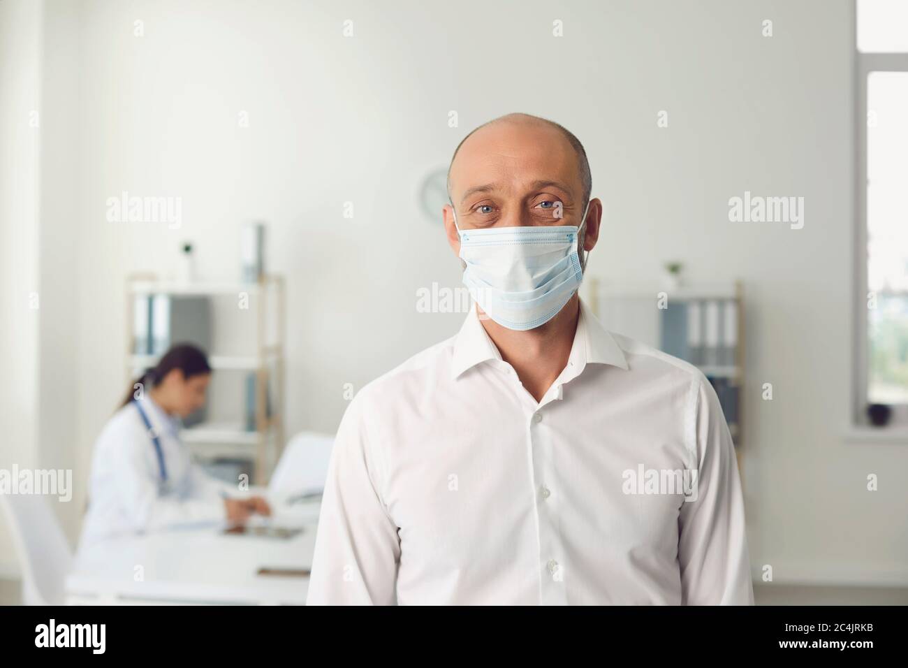 Homme âgé portant un masque de protection lors de la visite chez un médecin à l'hôpital, espace vide. Patient et médecin spécialiste à la clinique Banque D'Images
