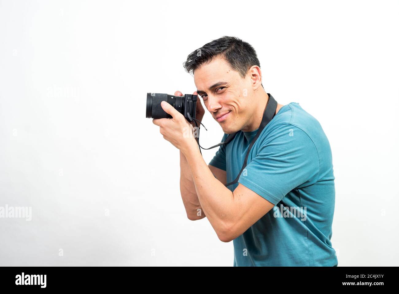 Homme souriant avec un appareil photo entre les mains regardant l'appareil photo. Vue latérale. Photo intermédiaire. Fond blanc. Banque D'Images