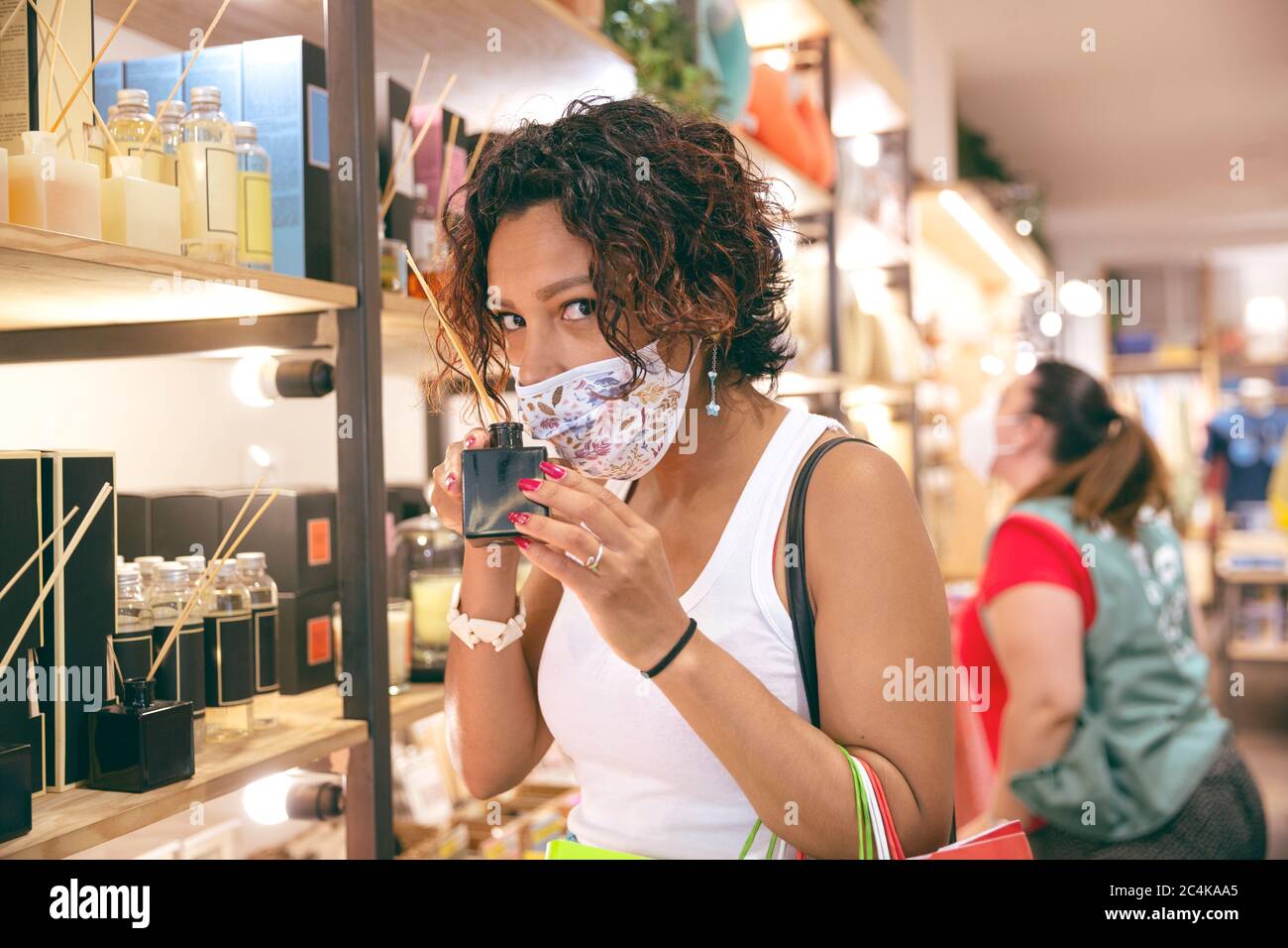 Femme à la peau brune avec un masque facial faisant du shopping dans un magasin. Mise au point sélective. Concept de nouvelle normalité dans la période Covid-19. Banque D'Images