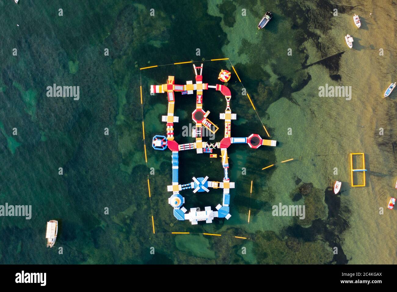 Parc aquatique gonflable vue plongeante flottant sur une mer Méditerranée turquoise Banque D'Images