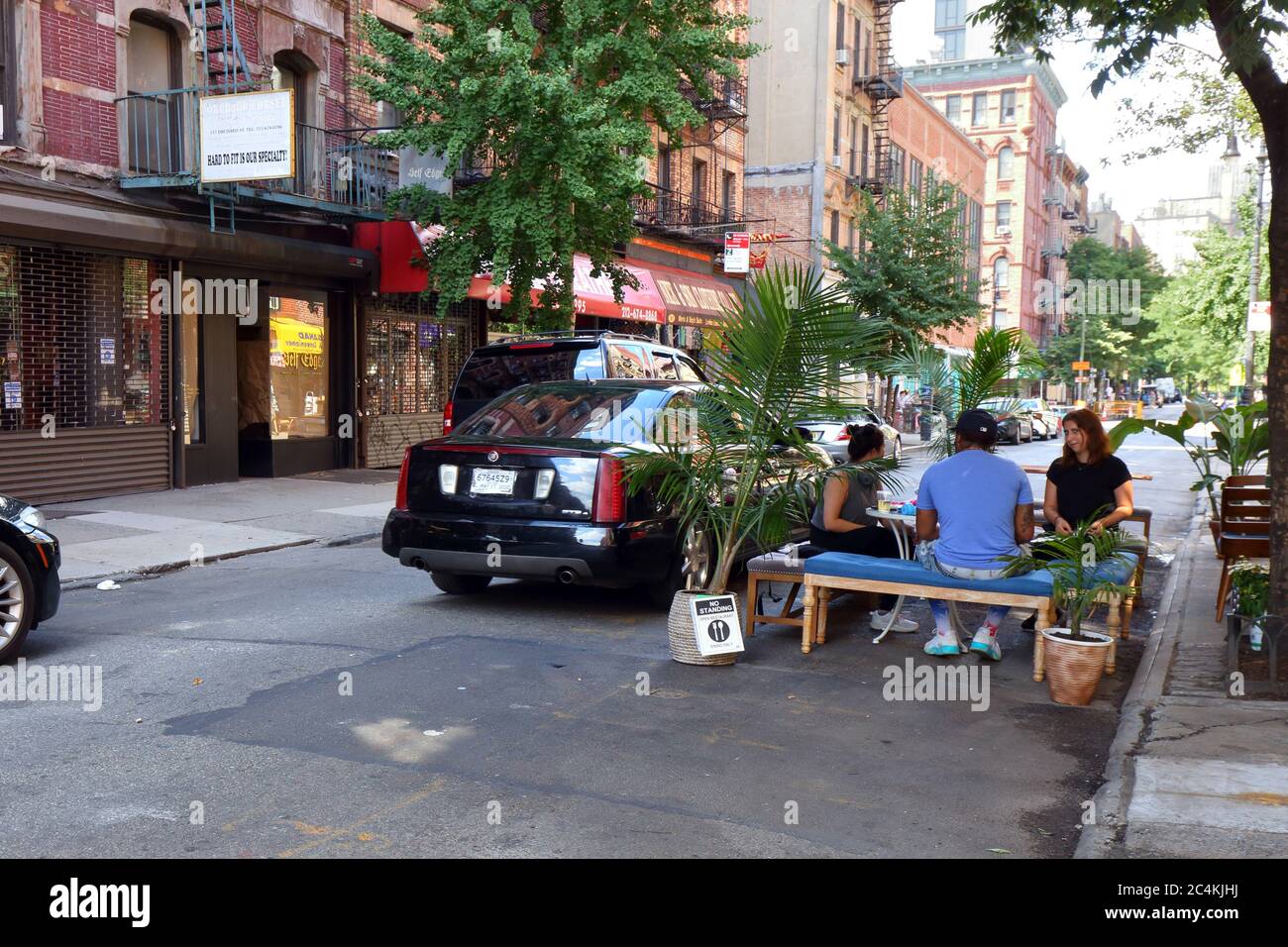 New York, NY. 26 juin 2020. Une voiture avec une plaque d'immatriculation en papier tente de passer devant un vus mal garé et un parlet (extension de trottoir sur une voie de stationnement pour des repas en plein air socialement éloignés) avec des personnes à l'extérieur de Tzarevna sur Orchard St à Manhattan dans le cadre de la réouverture de la phase 2 de New York City. Certaines rues du Lower East Side ont été fermées à la circulation sous la deuxième incarnation de NYC Open Streets, ce qui permet de manger plus sans stress. La circulation dans les rues ouvertes 2,0 n'est pas imposée par la police et s'appuie sur les défenseurs locaux, et les gens pour garder les rues piétonnes orientées. Banque D'Images