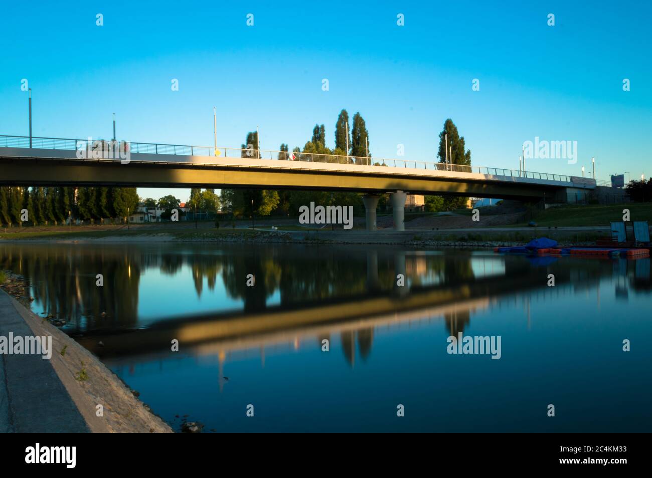 À la lumière du soleil couchant, le pont est réfléchi par l'eau de la rivière Banque D'Images