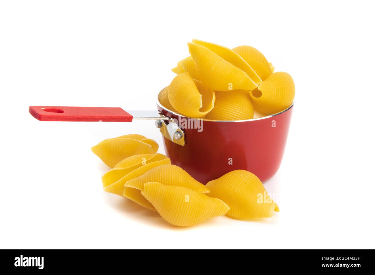 un petit pot de cuisson rouge rempli de pâtes à coque jumbo isolées sur blanc Banque D'Images