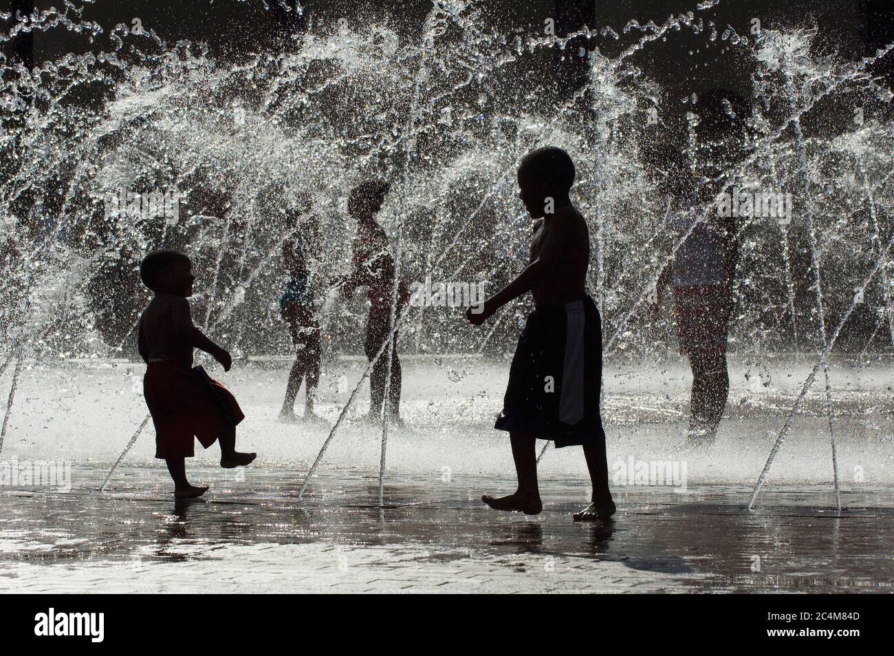 Enfants jouant dans la fontaine d'eau pendant la chaleur estivale Banque D'Images