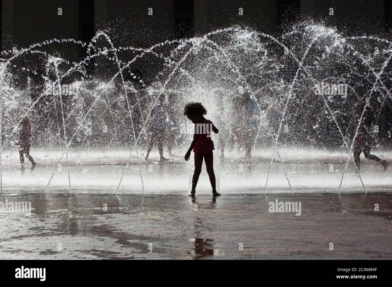 Enfants jouant dans la fontaine d'eau pendant la chaleur estivale Banque D'Images