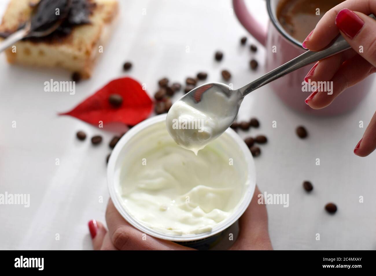 Femme mangeant du yaourt pour le petit déjeuner, une tasse de café frais et du pain grillé/ image conceptuelle d'un petit déjeuner sain Banque D'Images