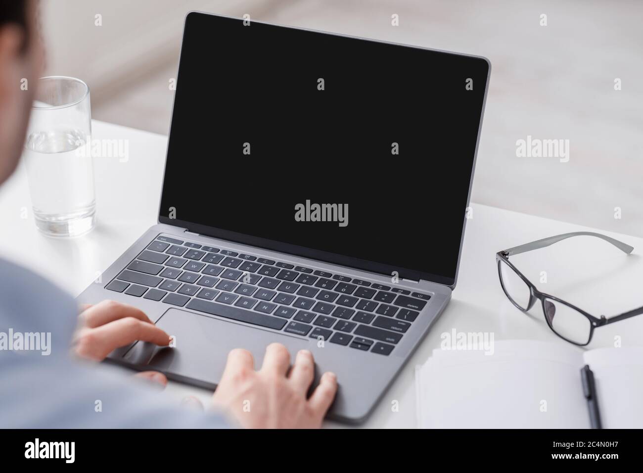 Conférence en ligne pendant le travail. L'homme tient les mains sur l'ordinateur portable et regarde le moniteur Banque D'Images