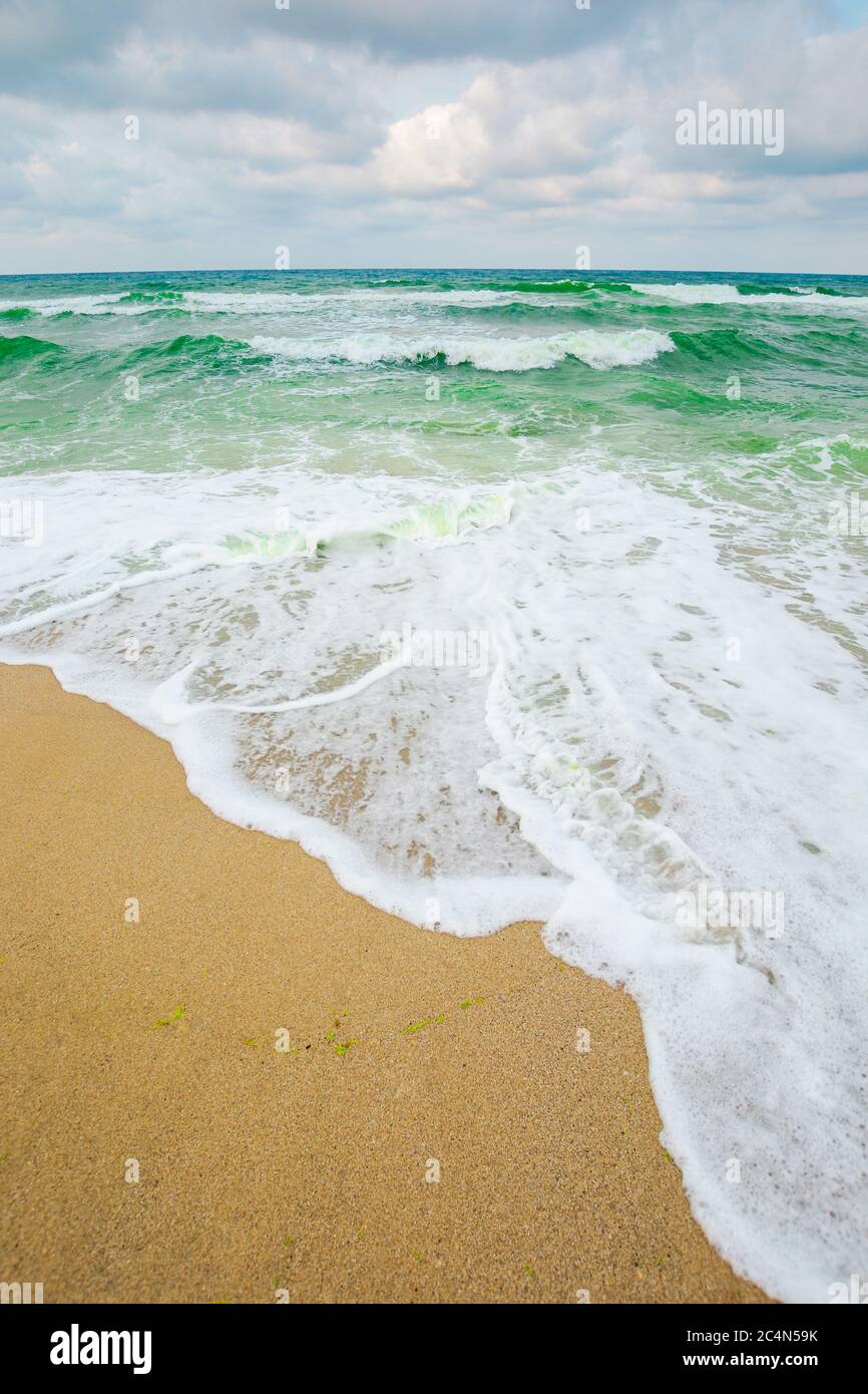 marée de la mer en soirée nuageux. vagues écrasant la plage de sable Banque D'Images