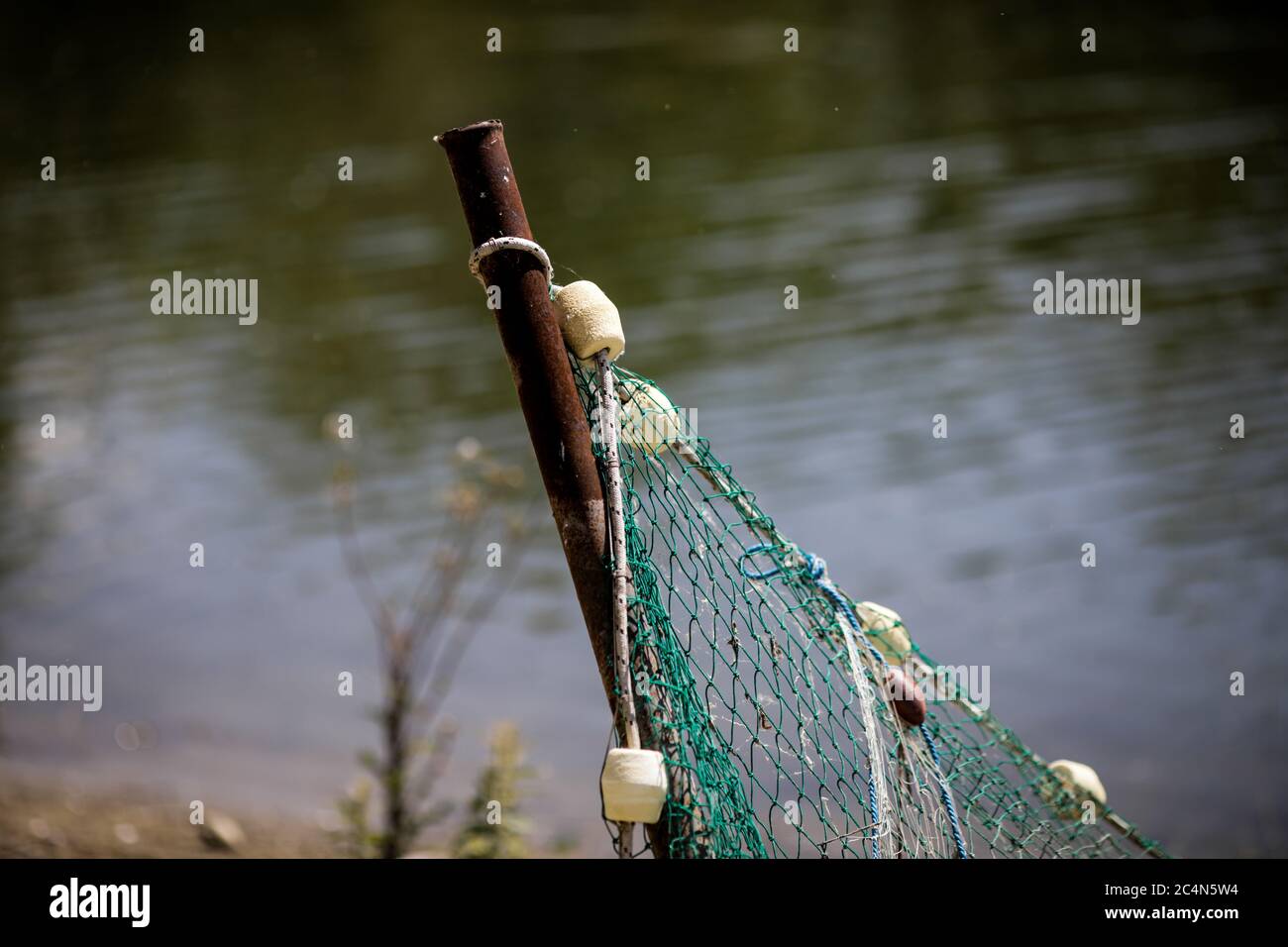 Détails avec un filet de pêche attaché à un poteau en métal sur une rive de rivière. Banque D'Images