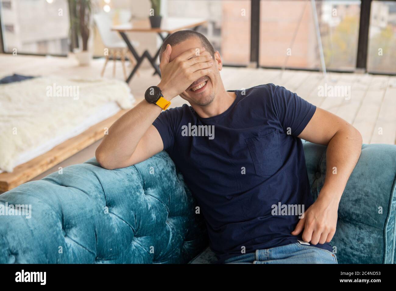 L'homme ferme son visage avec la main et sourire Banque D'Images