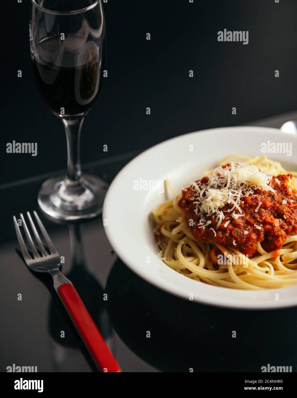 Dose verticale de pâtes avec sauce dans un bol la table avec un verre de  vin rouge Photo Stock - Alamy