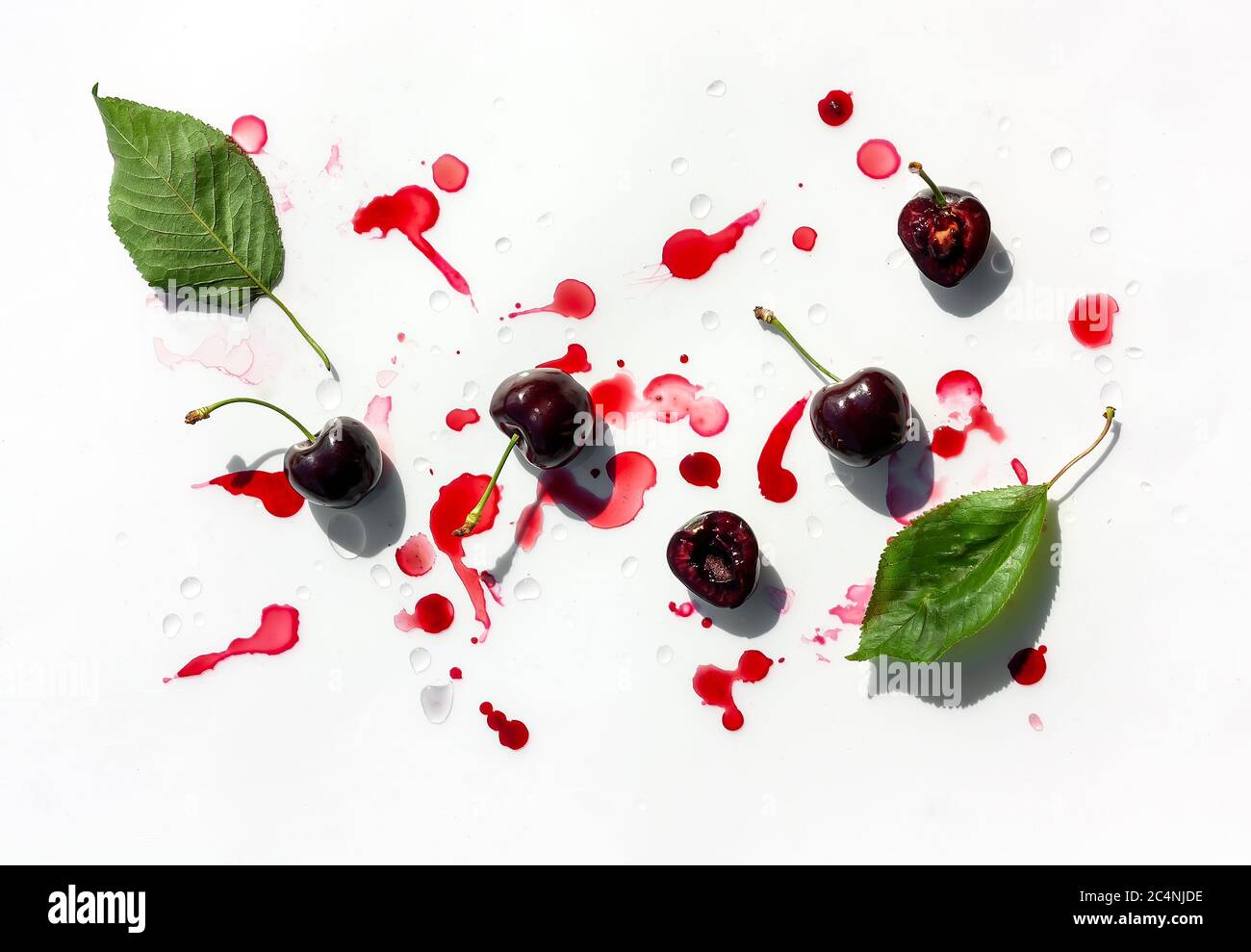 Mise en page estivale créative en cerisier. Fruits mûrs sur fond blanc avec gouttes de jus de cerise. Vue de dessus. Copier l'espace Banque D'Images