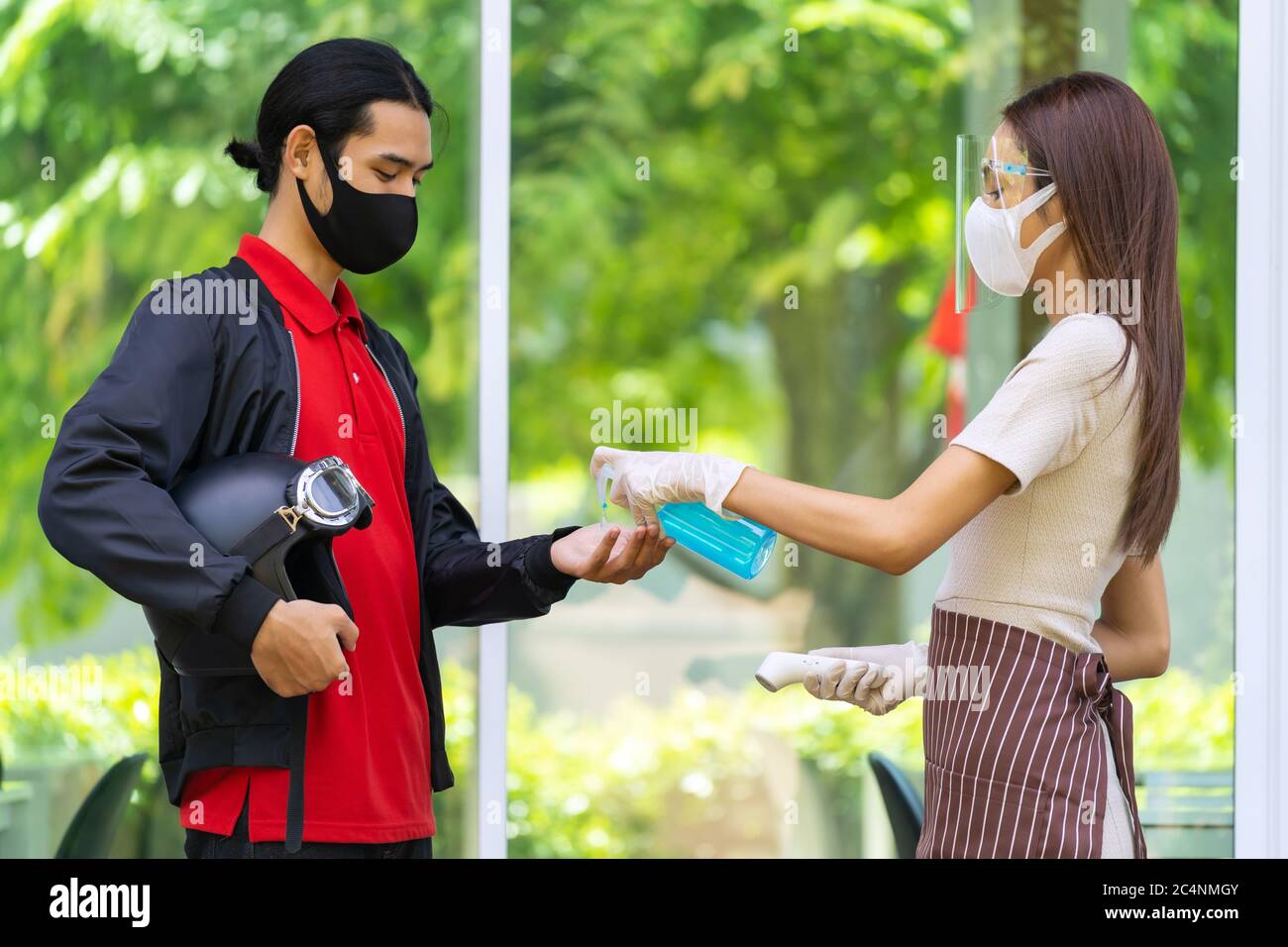 Le personnel de la serveuse du restaurant pousse le gel désinfectant pour les mains pour le liveur afin de l'hygiène avant de faire la queue au restaurant. Restaurant Nouveau concept normal après co Banque D'Images