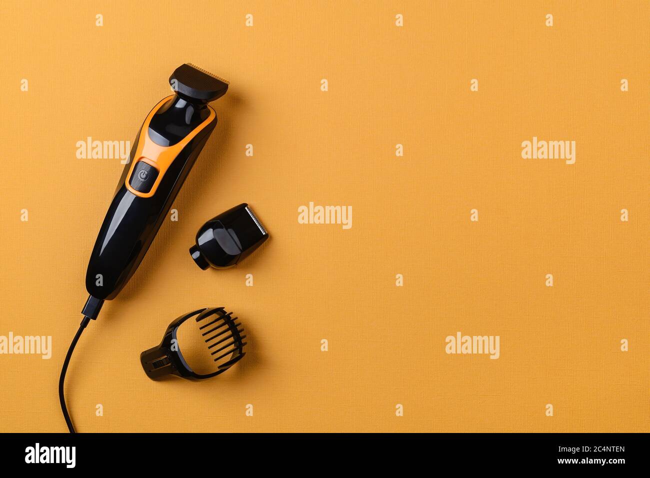 Tondeuse à cheveux électrique sur fond jaune texturé. Outil professionnel de coiffure pour couper les cheveux. Coupe de cheveux au coiffeur ou à la maison. Banque D'Images