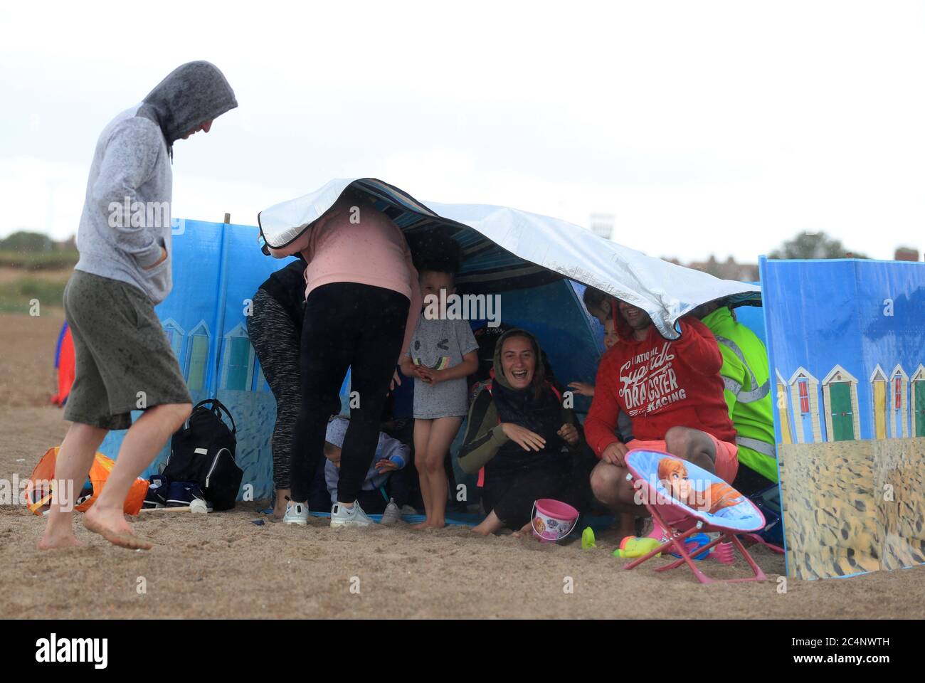 Une famille se protège du temps sur la plage de Skegness, car la pluie, le vent et les
