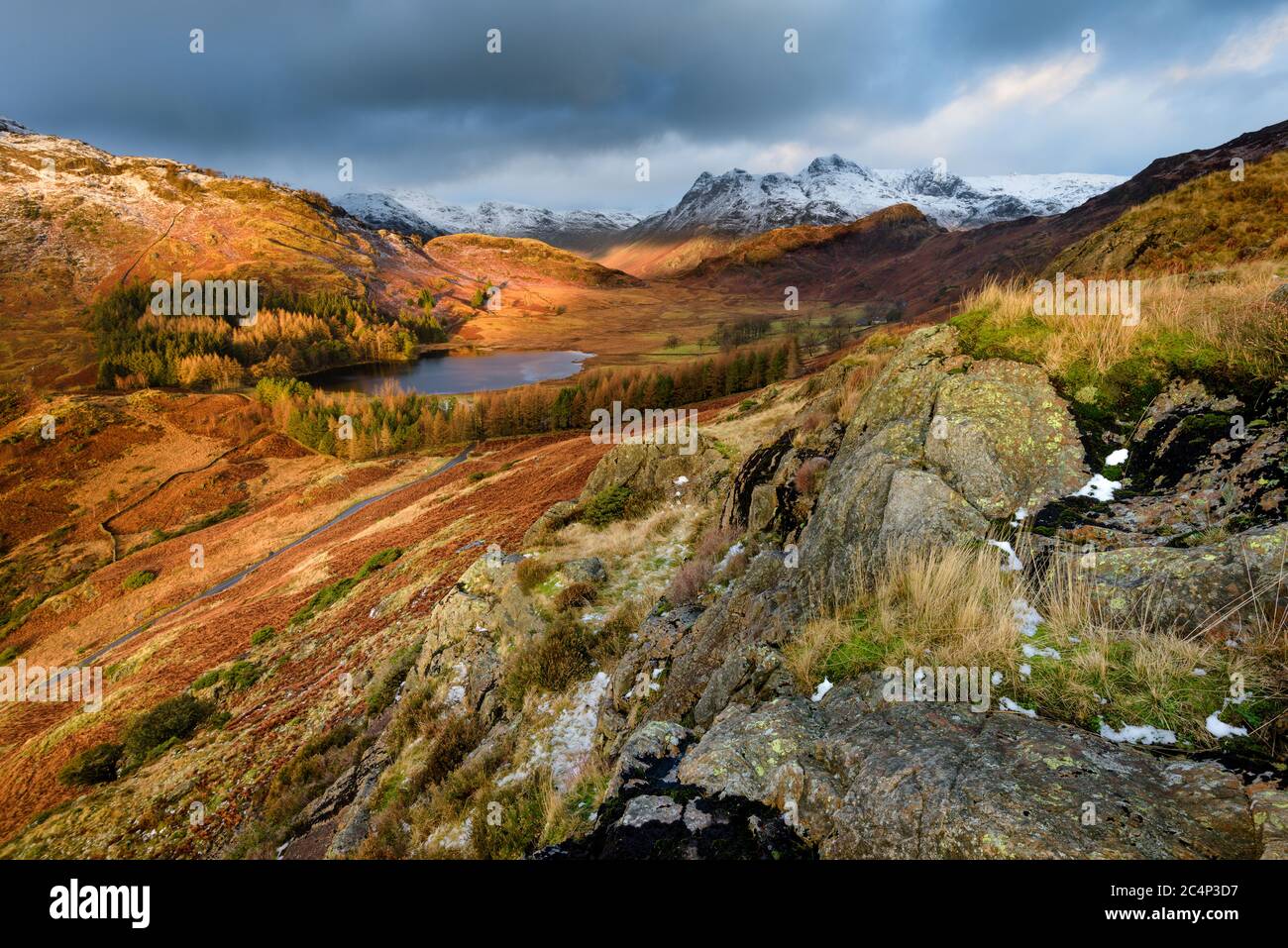 Vue panoramique sur le paysage spectaculaire de Blea Tarn avec neige sur les pikes de Langdale et les nuages sombres. Lake District, Royaume-Uni. Banque D'Images