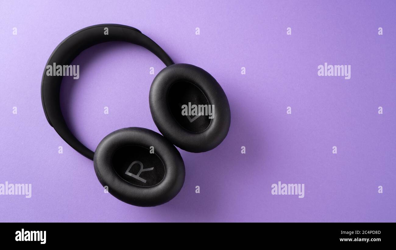 écoutez votre musique en permanence. le meilleur cadeau pour les adolescents. casque sans fil noir sur fond violet. Banque D'Images