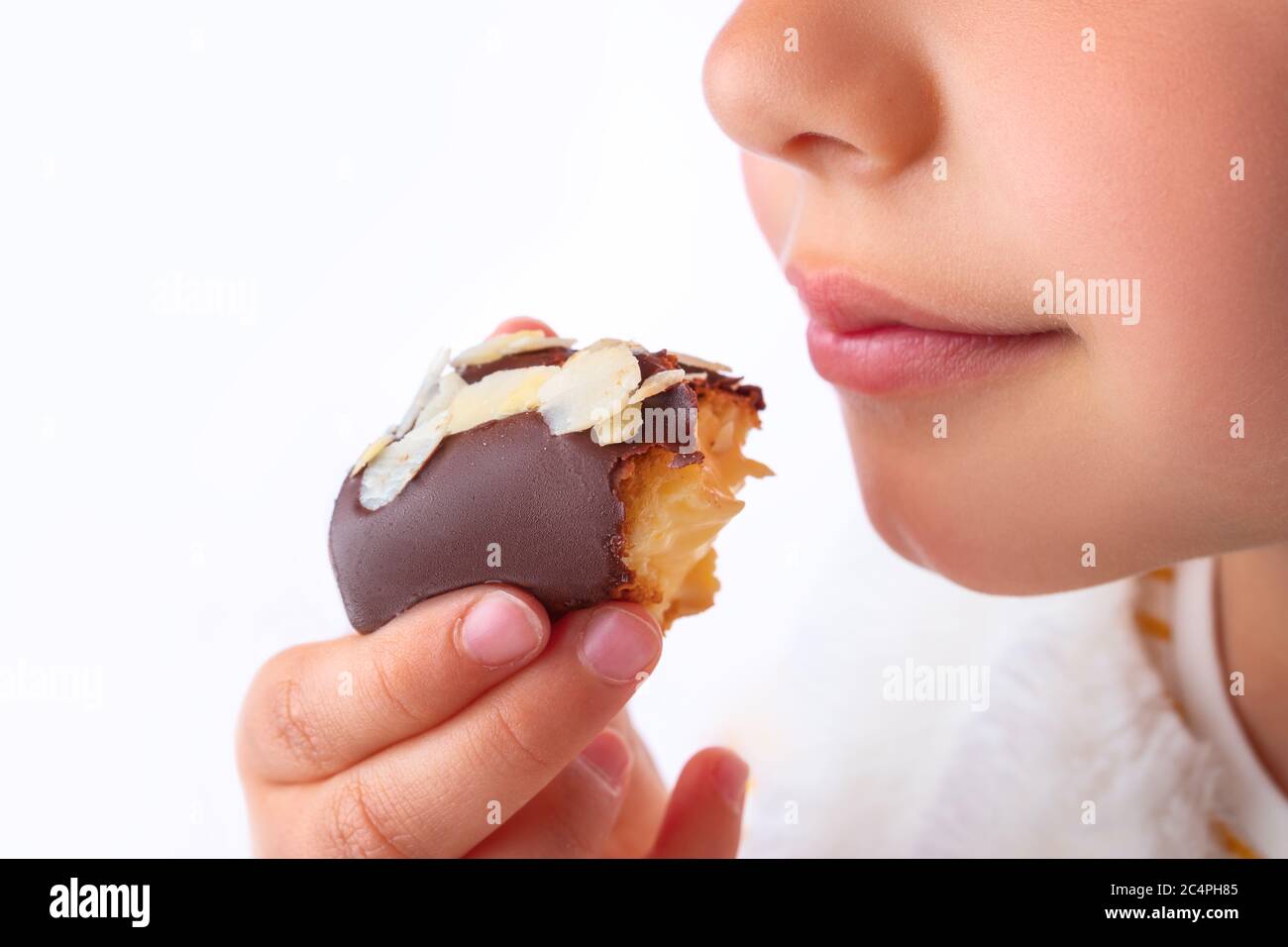 Petite fille goût la pâtisserie d'eclair comme un pro - odeur, morsure, manger. Banque D'Images