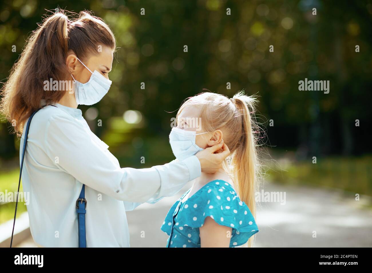 La vie durant la pandémie de Covid-19. Belle mère et fille à l'extérieur dans le parc de la ville portant un masque médical. Banque D'Images