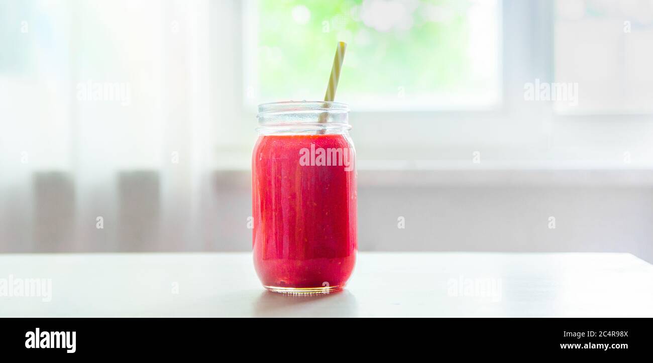 Smoothie rouge frais sur une table de cuisine blanche. Repas et boissons d'été. Bannière concept. Smoothie framboise et fraise. Banque D'Images