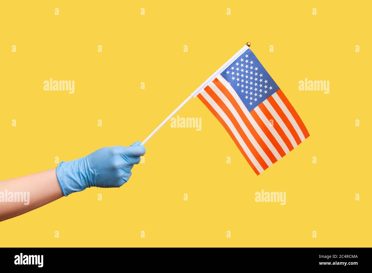 Profil vue latérale gros plan de la main humaine en gants chirurgicaux bleus tenant le drapeau national des États-Unis. États-Unis d'Amérique. Jour national d'indépendance - 4e j Banque D'Images