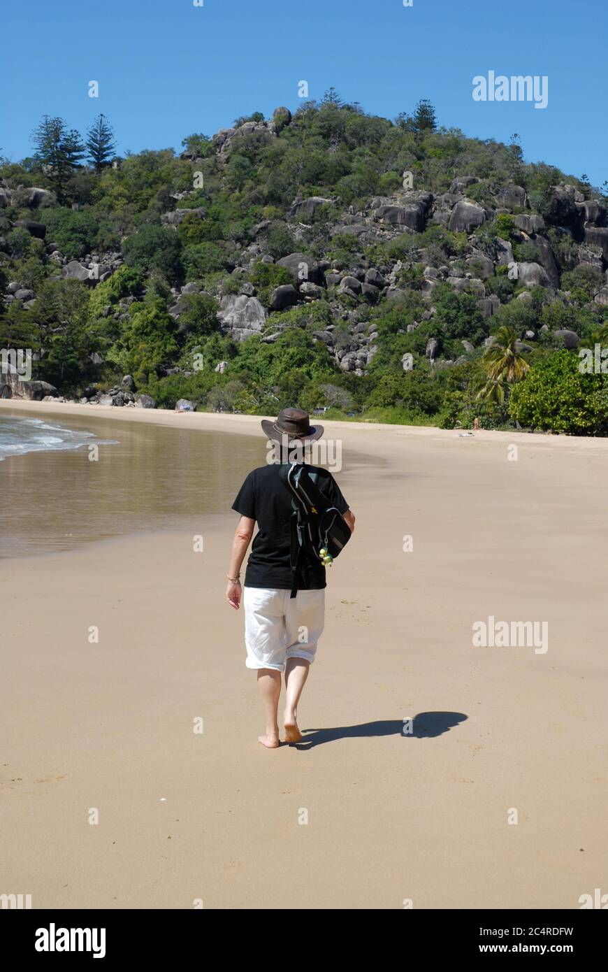 Vue arrière d'une femme qui s'éloigne avec un ukulele sur son épaule, sur la plage de radical Bay sur l'île Magentic, Queensland, Australie Banque D'Images