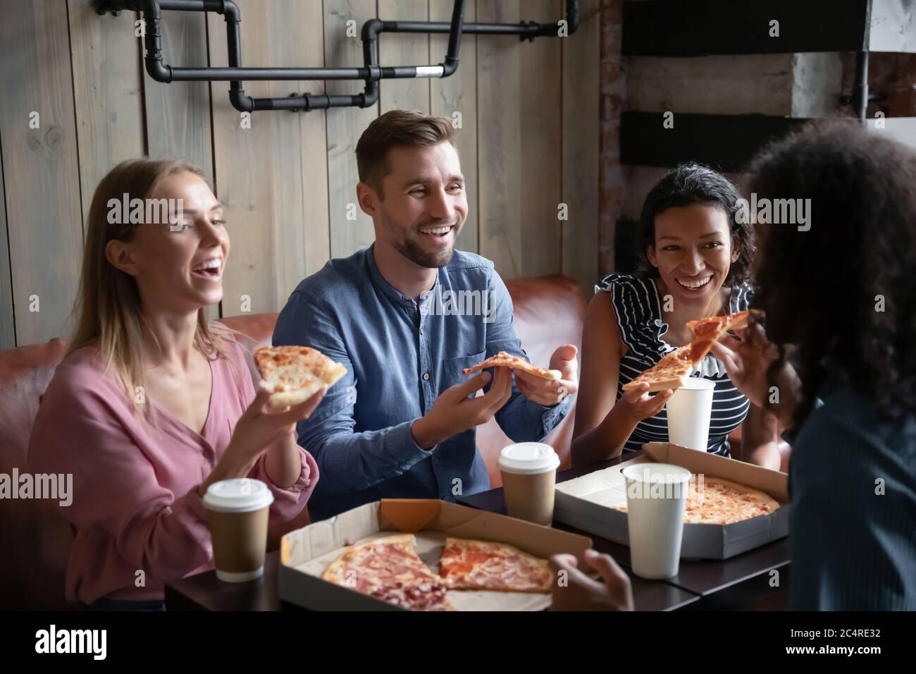 Quatre meilleurs amis multiethniques mangent de la pizza boire du café dans le café Banque D'Images