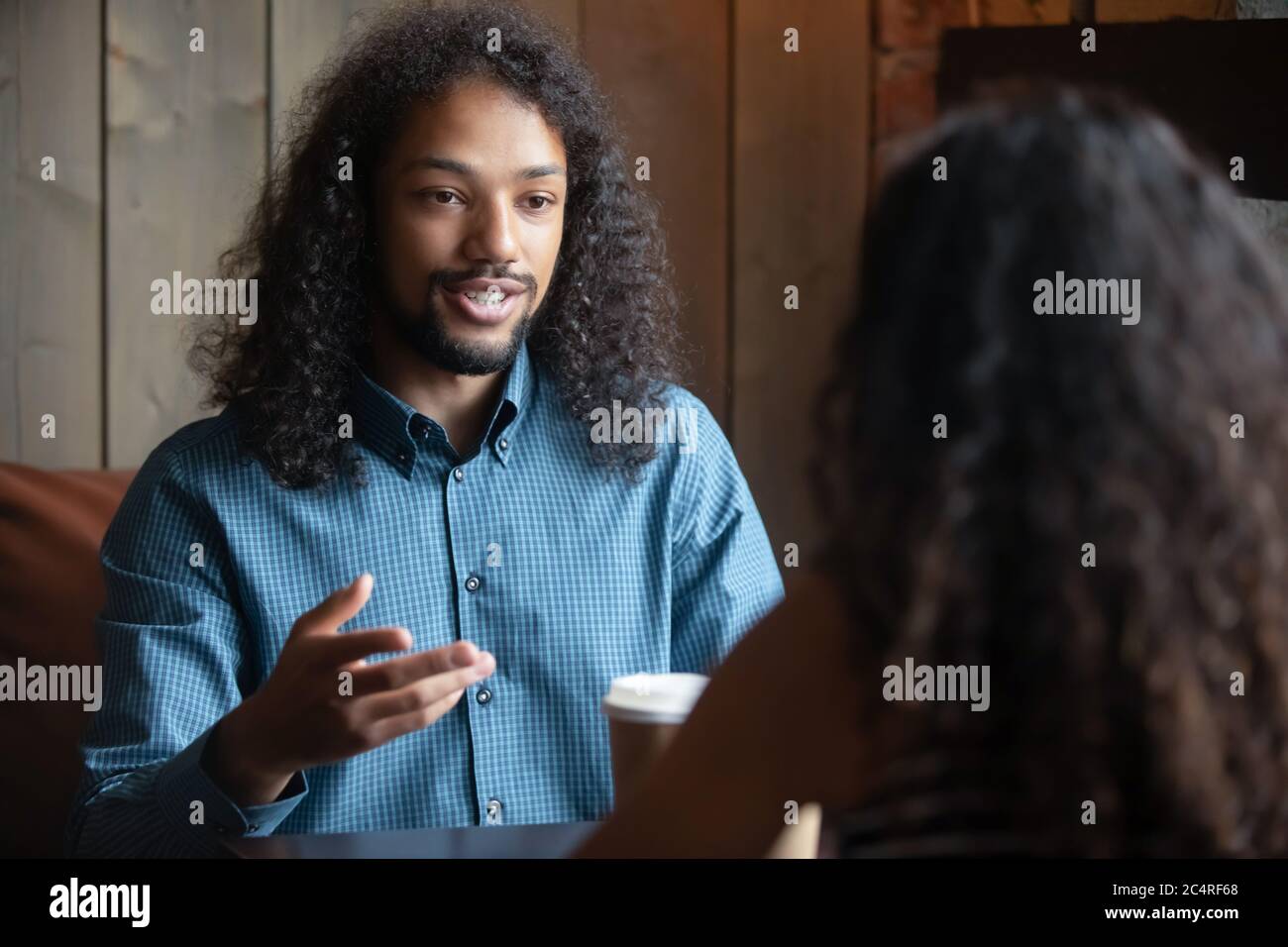 Un homme africain assis dans un café avec une fille pendant la datation de vitesse Banque D'Images