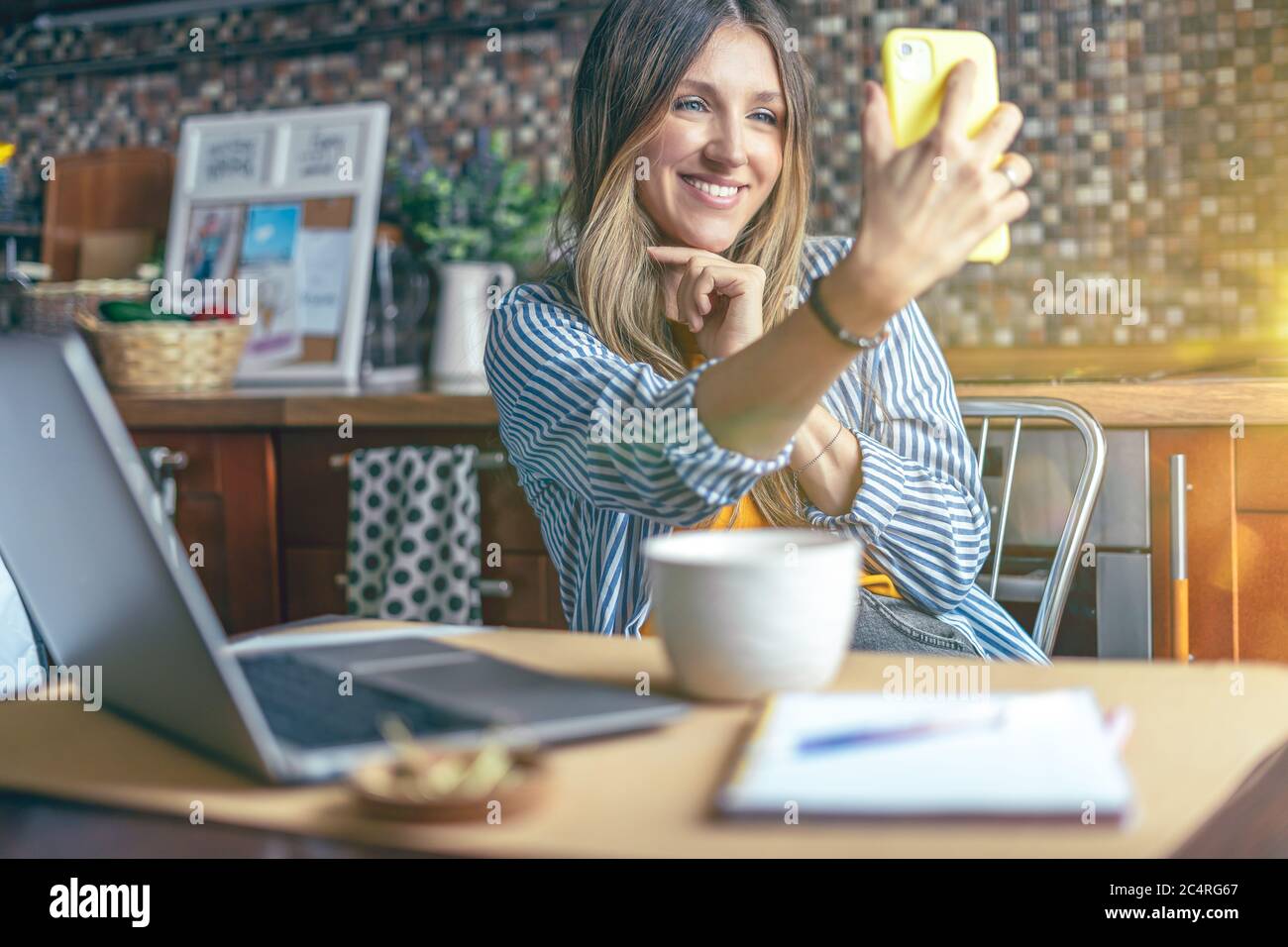 Femme d'affaires ayant un appel vidéo facetime. Femme fait selfie. Une fille heureuse et souriante travaillant à domicile kithcen. Utilisation de l'ordinateur et du pho mobile Banque D'Images
