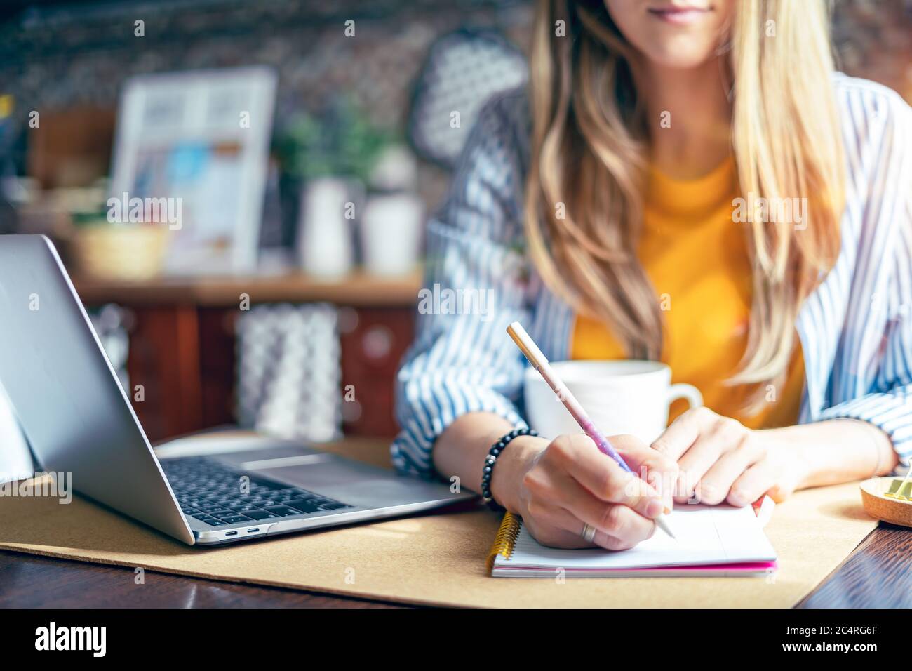 Formation à distance et travail en ligne. Une femme d'affaires écrit dans un carnet de bureau. Une fille heureuse et souriante travaillant à domicile kithcen et dr Banque D'Images