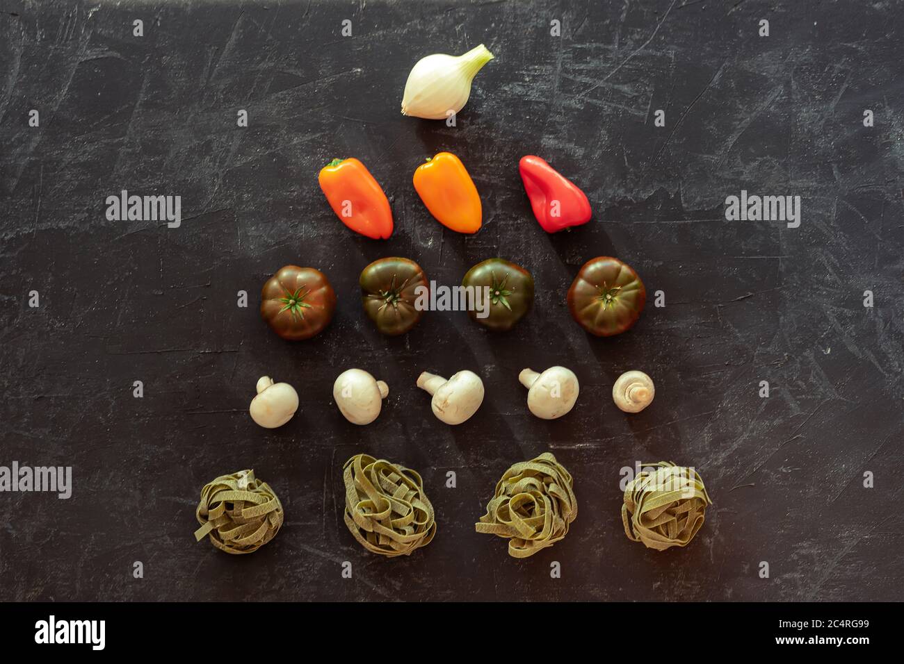 Spaghetti verts, champignons, tomates, poivron et oignon sur fond noir. Nourriture végétalienne. Cuisine italienne. Vue de dessus, plan d'appartement Banque D'Images
