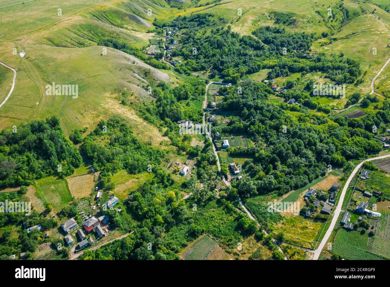 Village rural parmi les collines verdoyantes et les champs agricoles en campagne , vue aérienne de drone. Banque D'Images