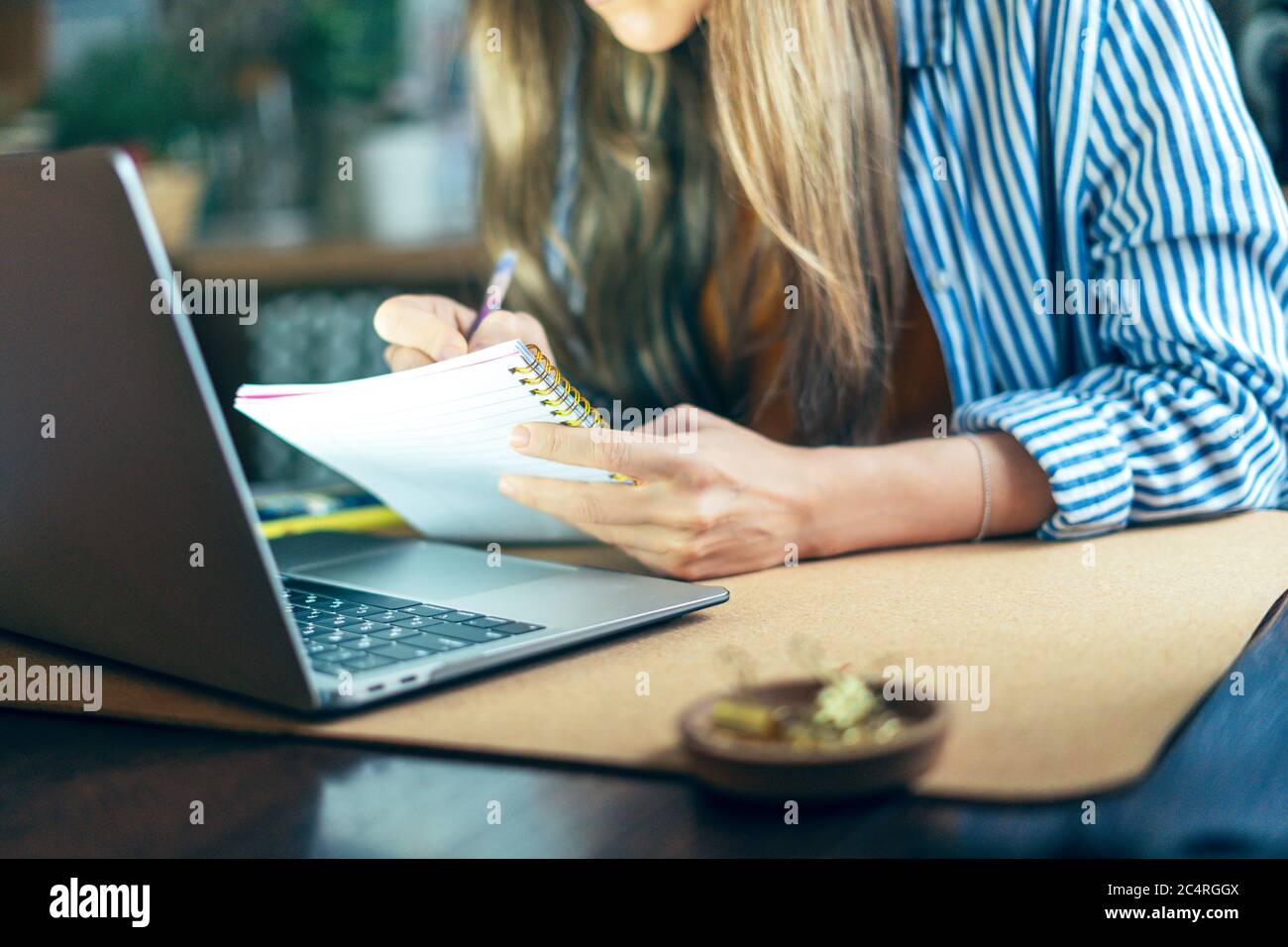 Une femme d'affaires écrit dans un ordinateur portable sur le bureau et regarde l'ordinateur. Une fille heureuse et souriante travaillant à domicile kithcen. Utilisation de l'ordinateur portable et du sh en ligne Banque D'Images