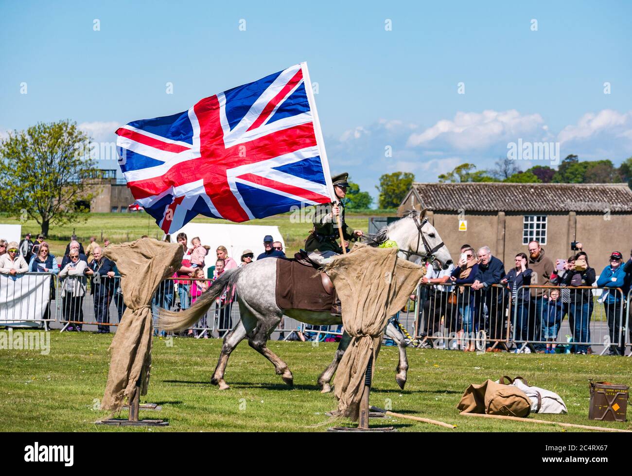 Les amis d'Onno équipe de cascades équestres avec un soldat à cheval portant un grand drapeau de l'Union Jack, événement de guerre, Fortune est, Lothian est, Écosse Banque D'Images